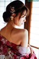 A woman in a red and white kimono looking out a window.