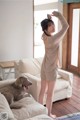 A woman standing on a couch next to a dog.