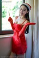 A woman in a red dress and a santa hat holding a knife.