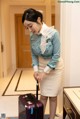 A woman in a blue shirt and white skirt holding a purple suitcase.