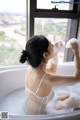 A woman taking a bath in a bathtub with foam.