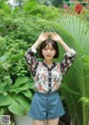 A woman standing in front of a lush green plant.