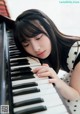 A young woman is playing the piano with her eyes closed.