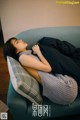 A woman laying on a blue couch with a blanket over her head.