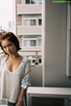 A woman standing on a balcony next to an air conditioner.