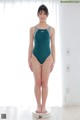 A woman in a green swimsuit standing on a scale.