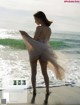 A woman standing on a beach next to the ocean.